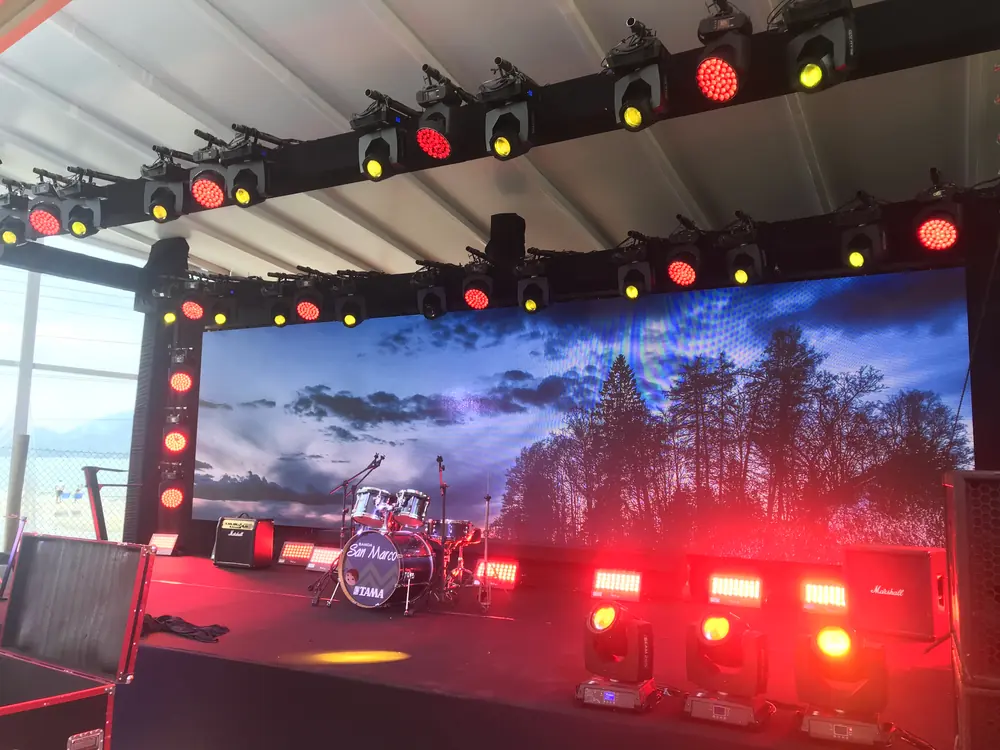 Palco com iluminação vermelha e amarela e telão de LED com paisagem